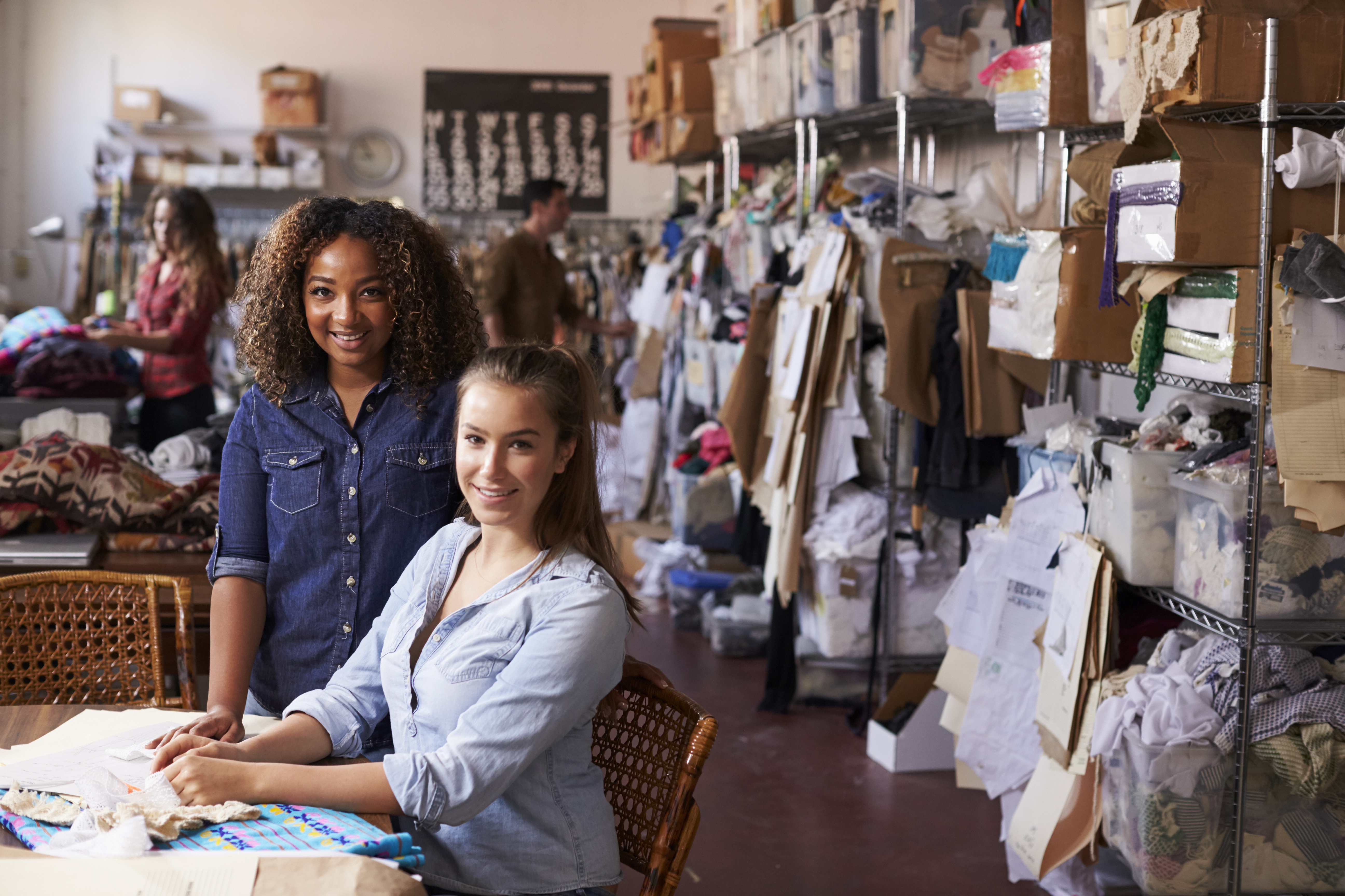 Trainee and manager at clothing design studio look to camera